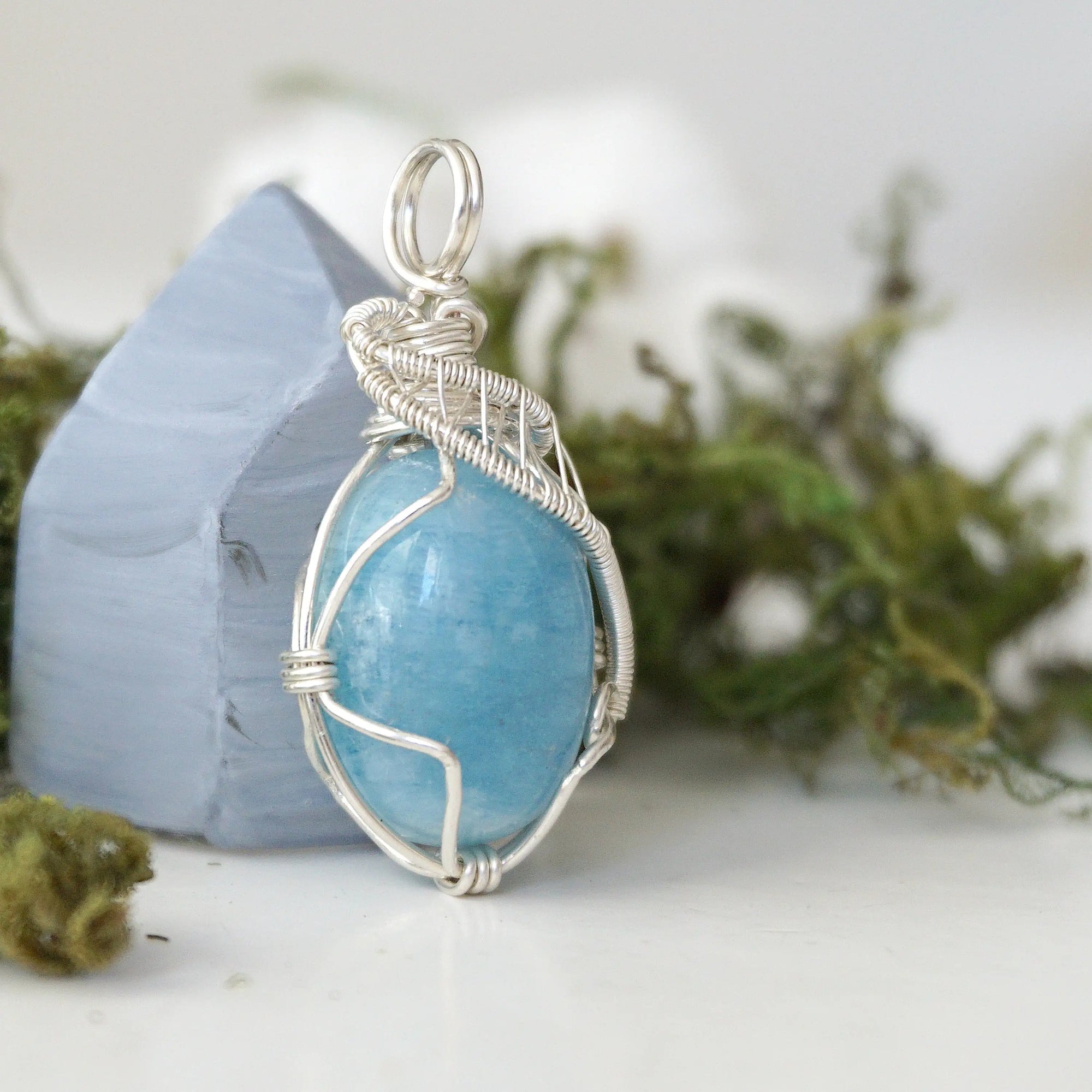 Right side view of aquamarine pendant showing intricate artisan wire wrapping and natural crystal shape