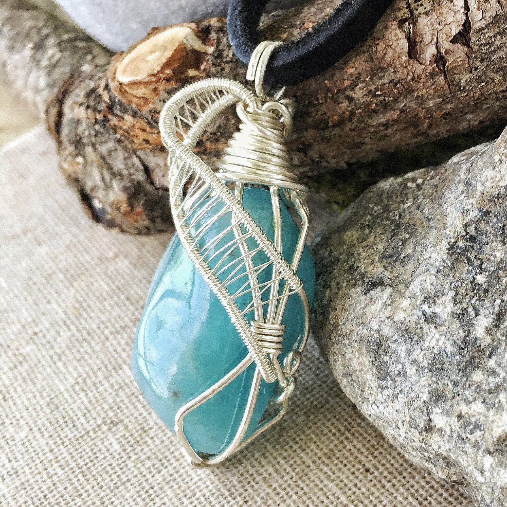 Side view of polished aquamarine pendant showing detailed artisan wire wrapping in sterling silver, men's design