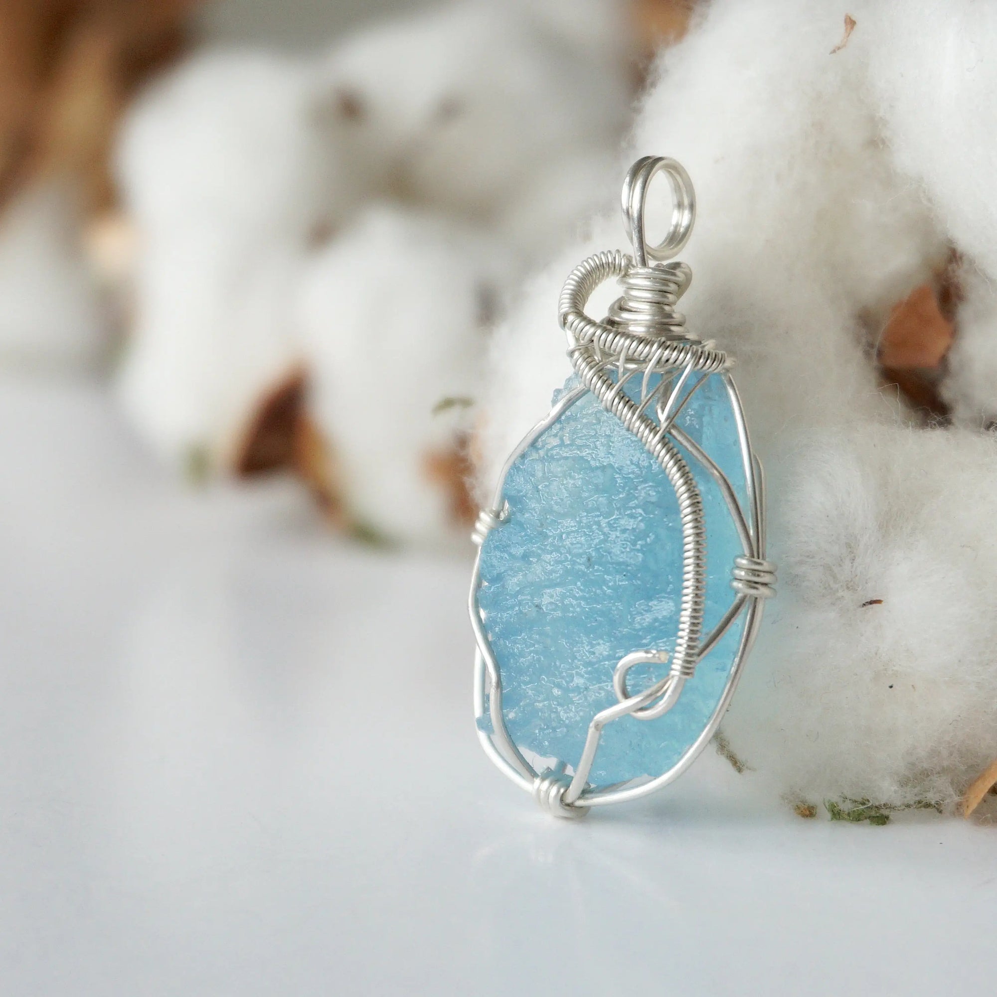 Side view of raw aquamarine pendant showing detailed artisan wire wrapping in sterling silver