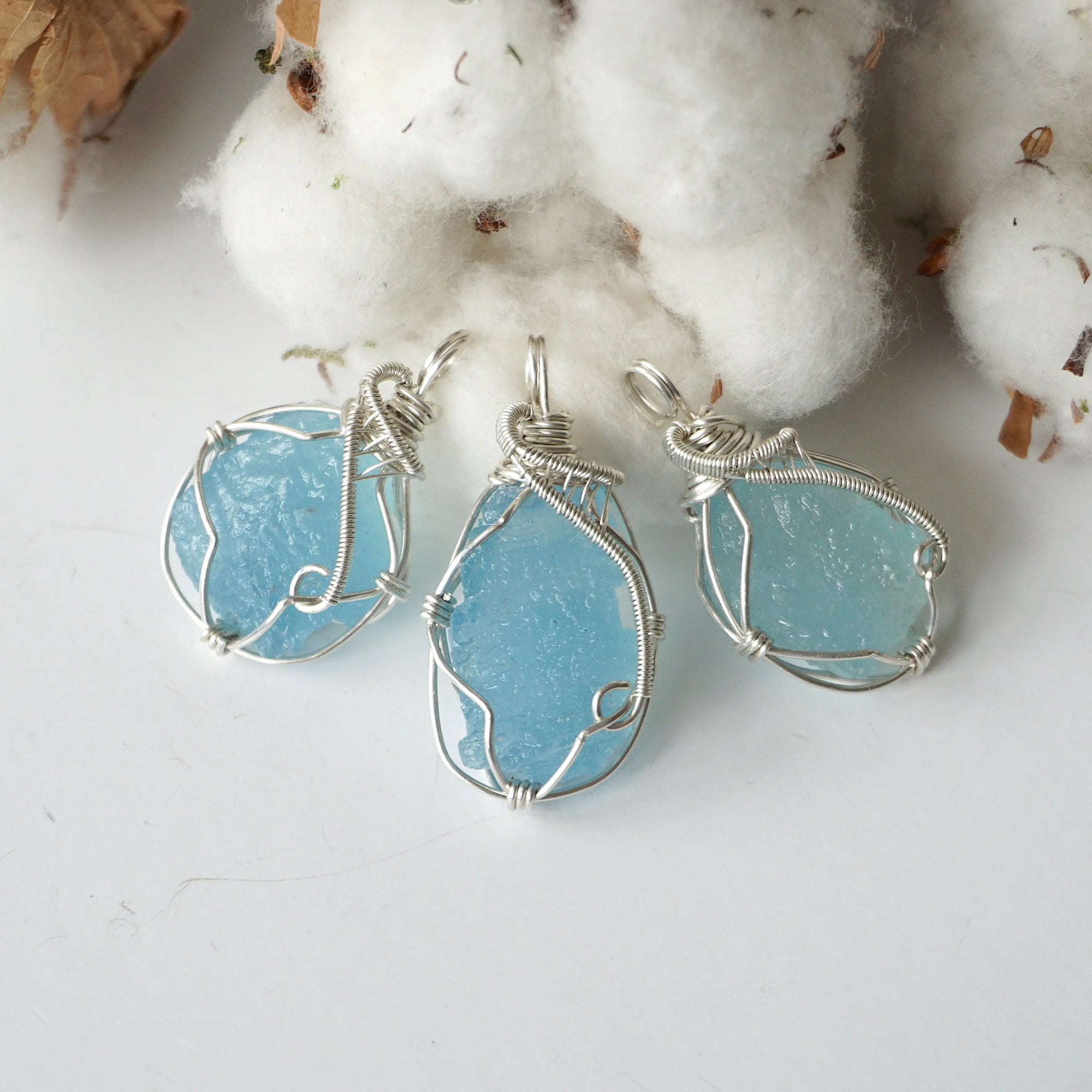 Three raw aquamarine pendants showing natural variation in size, shape, and blue color, Designs by Nature Gems