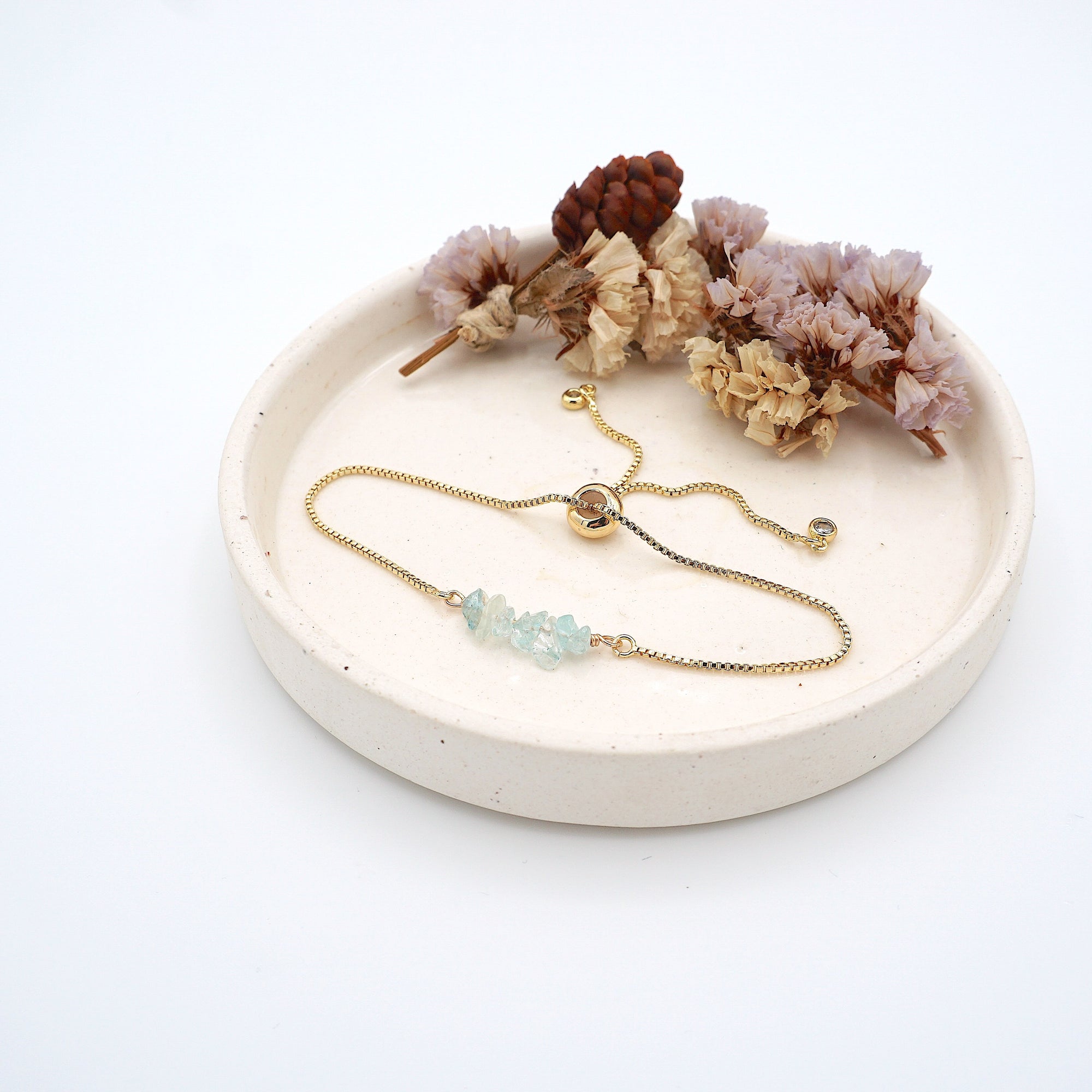 Handmade aquamarine bracelet displayed on ceramic tray showing natural blue crystals and gold chain - March birthstone gift for her