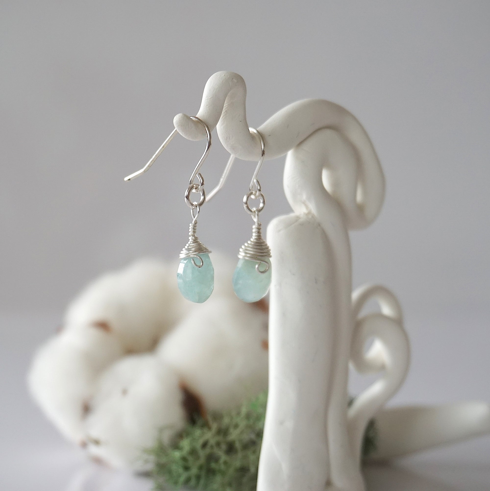 Side view of aquamarine sterling silver drop earrings showing wire wrapped natural faceted aquamarine, artisan craftsmanship, on a display – Designs by Nature Gems