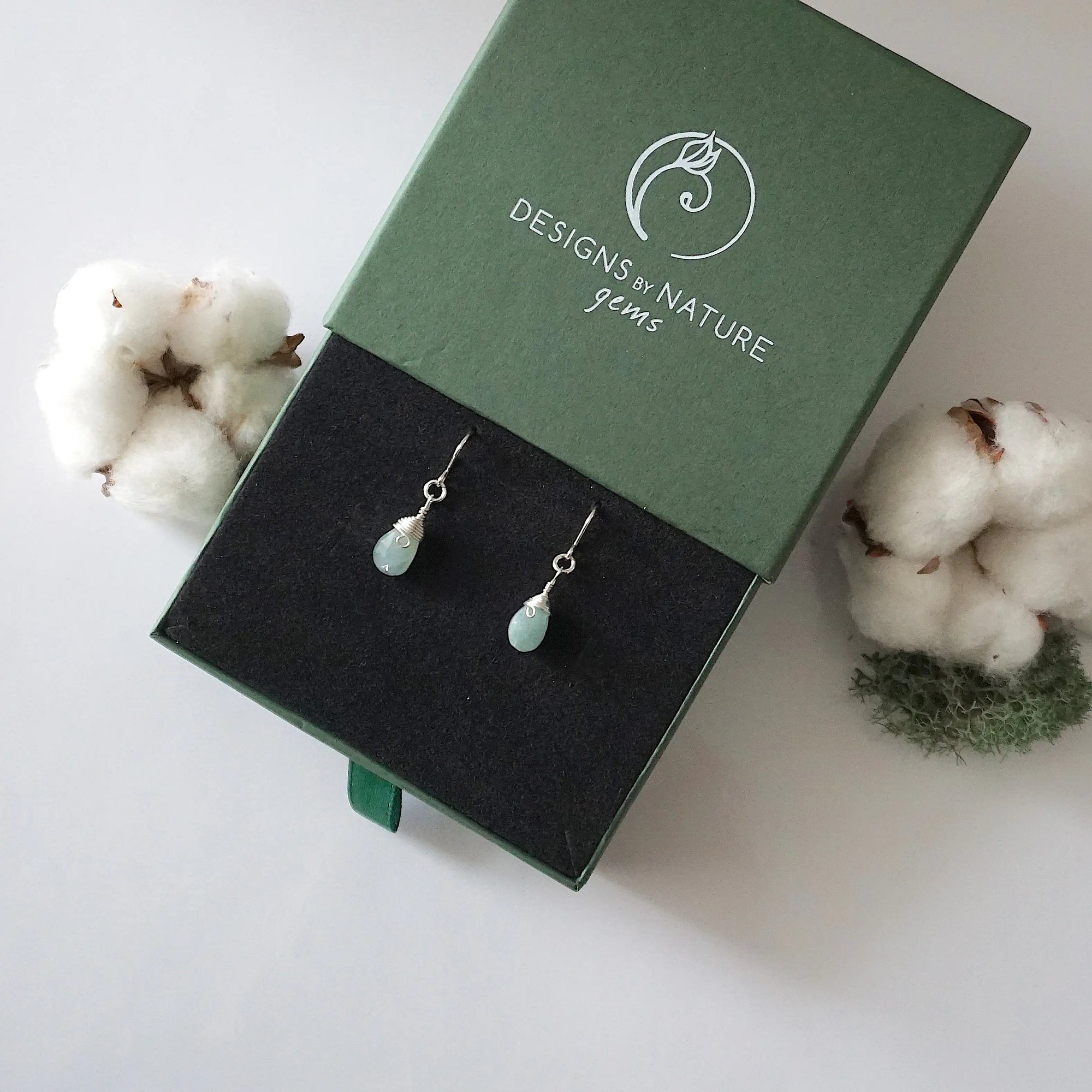 Aquamarine sterling silver drop earrings in branded Designs by Nature Gems jewelry box, showcasing handcrafted faceted aquamarine and sterling silver wire wrapping