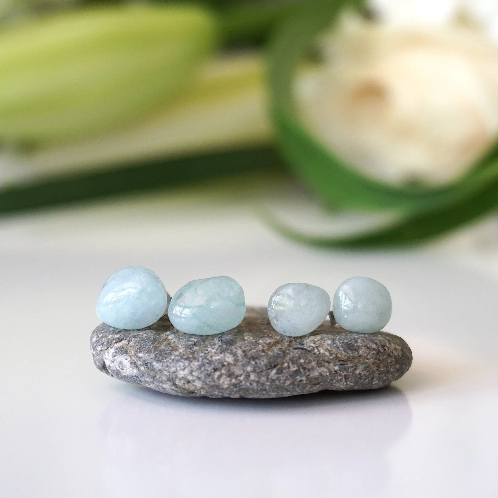 Two pairs of aquamarine stud earrings showing natural variation in size, shape, and blue color, raw stones, sterling silver