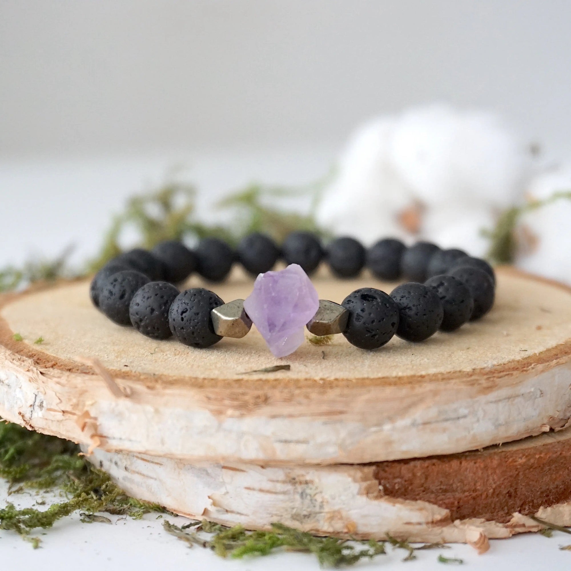 Detailed view of unisex stretch bracelet with 8mm black lava beads, raw amethyst (February birthstone) and pyrite accents