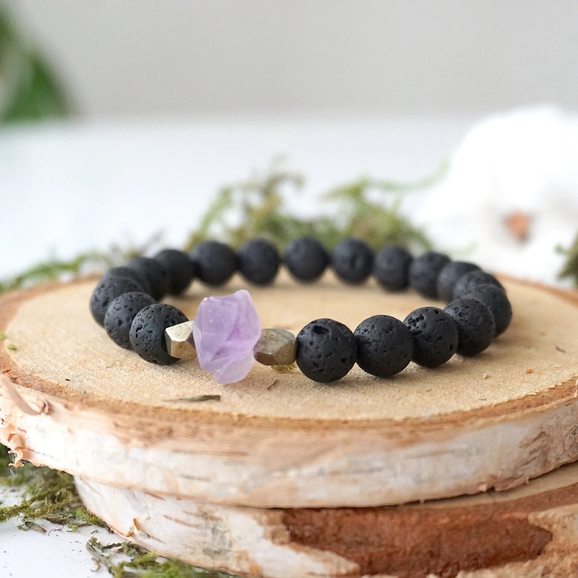Left side angle of black lava bead stretch bracelet with raw amethyst focal stone and pyrite crystal beads