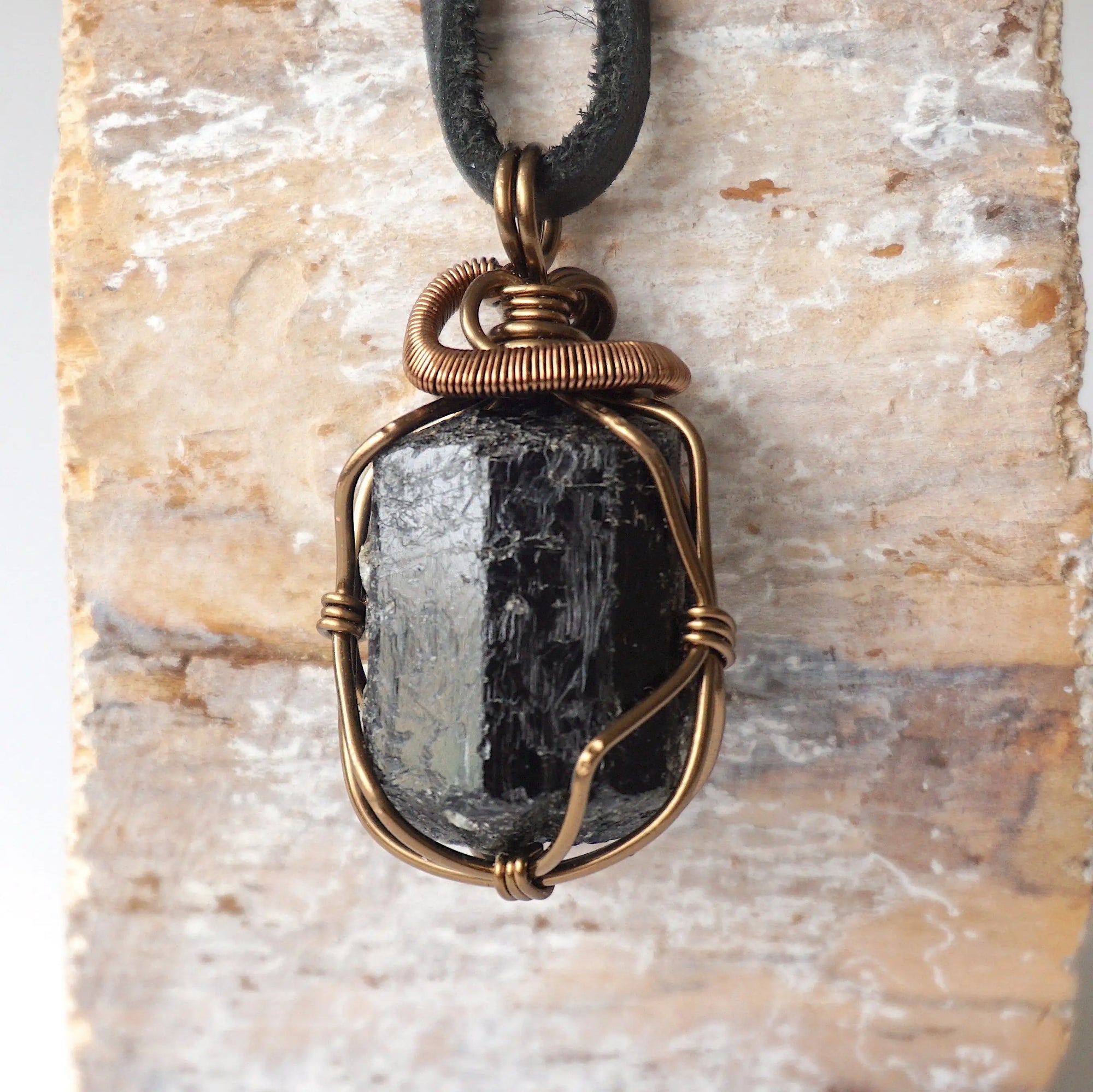 Detailed view of raw black tourmaline necklace on black leather cord, artisan wire wrapped pendant by Designs by Nature Gems.