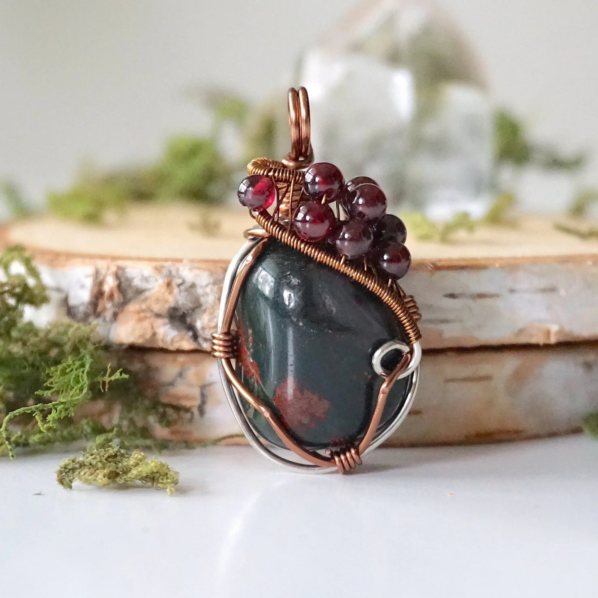 Detailed front view of a bloodstone pendant necklace with garnet accent beads and wire wrapped design