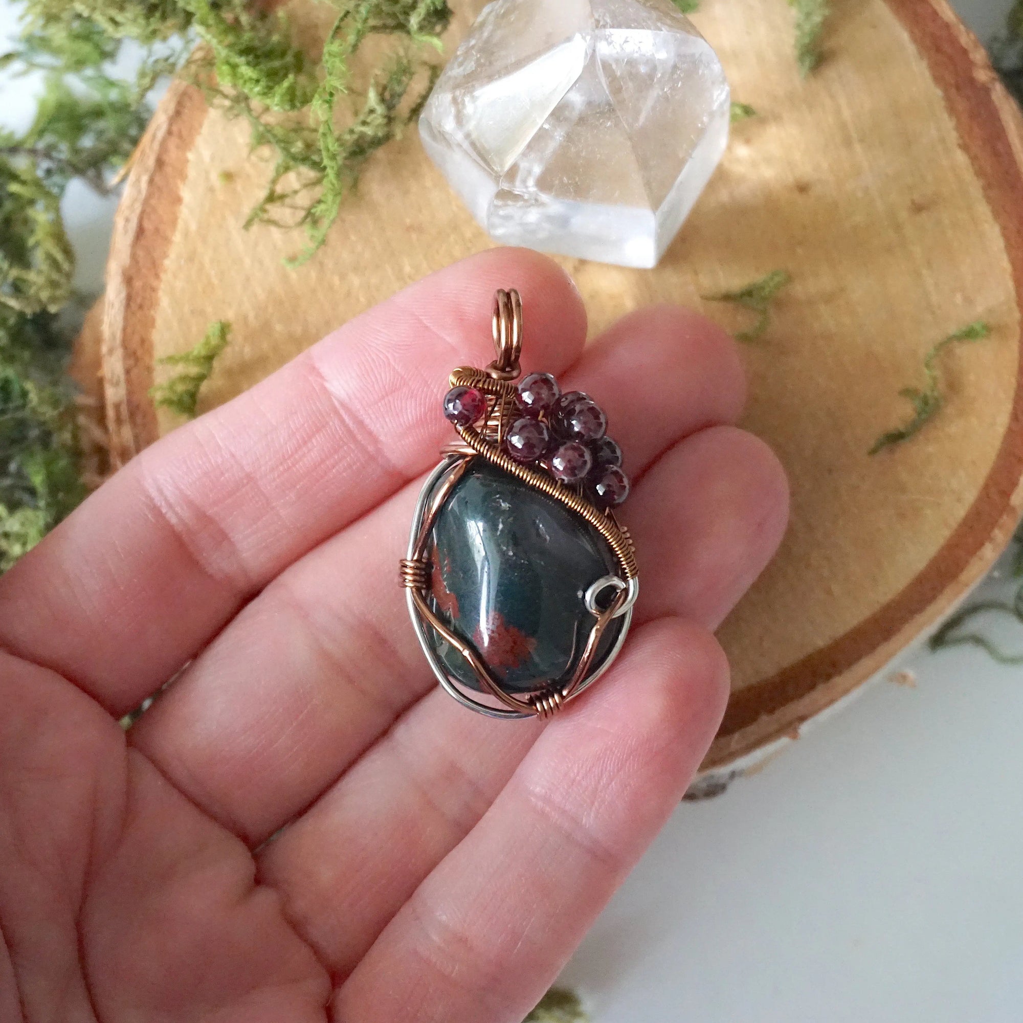 Bloodstone and garnet pendant necklace shown in hand for size reference