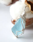 Side view of a blue topaz pendant showing the depth of the stone and its sterling silver wire wrap