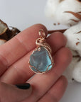 Blue topaz rose gold filled pendant held in the hand to show its size