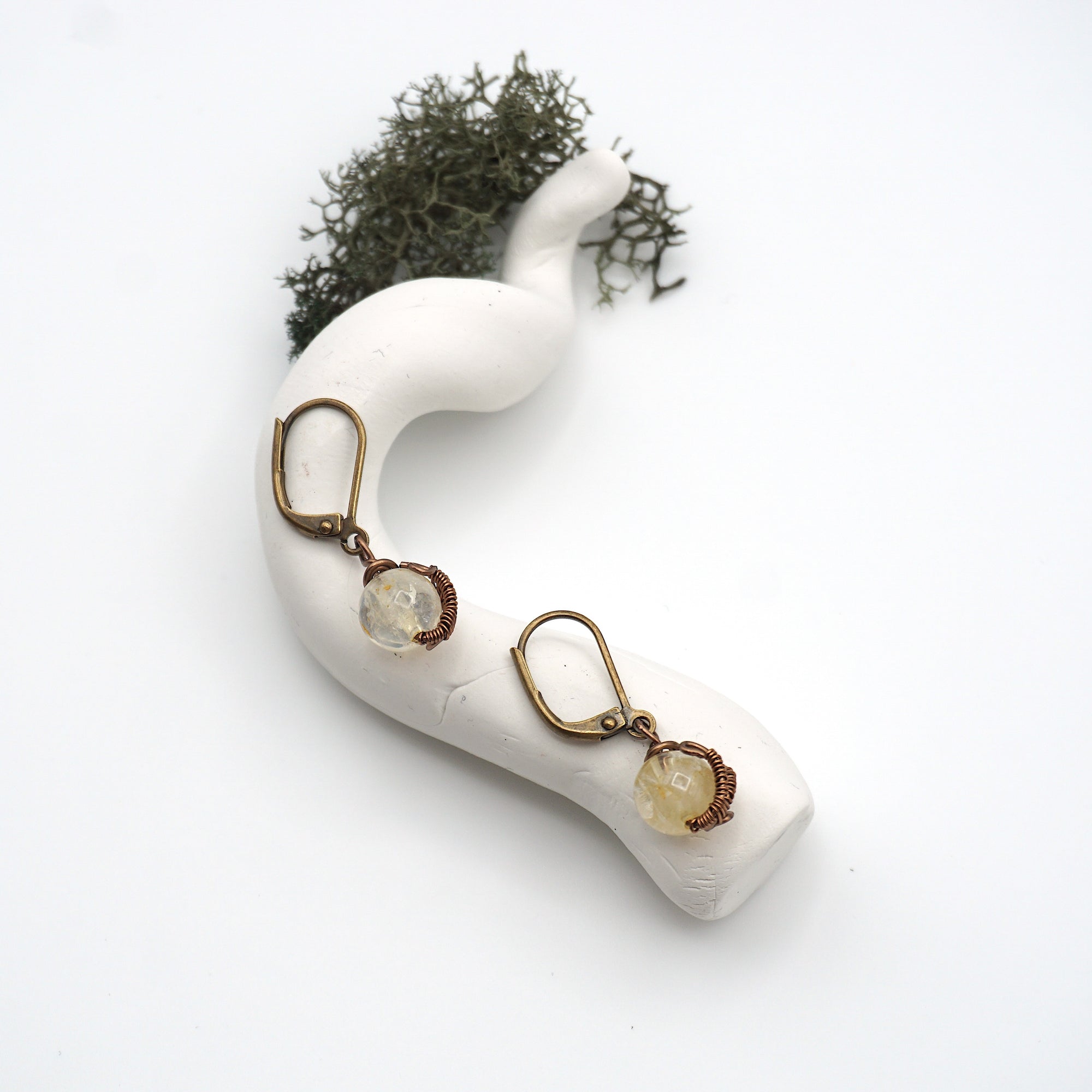 Bird’s eye view of citrine drop earrings laying flat on a display, showing detailed wire wrapping and gemstone color.