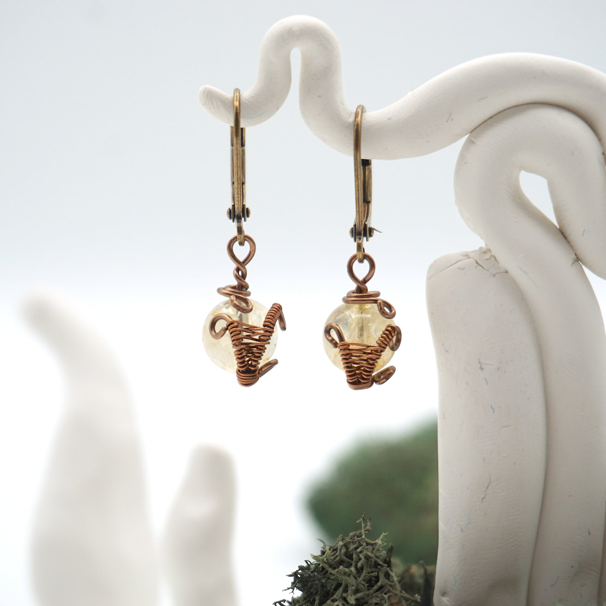 Close-up of handcrafted citrine drop earrings with antique bronze copper wire wrapping.