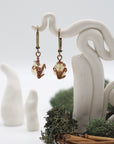 Front angle of citrine drop earrings hanging on a jewelry display, wire-wrapped design.