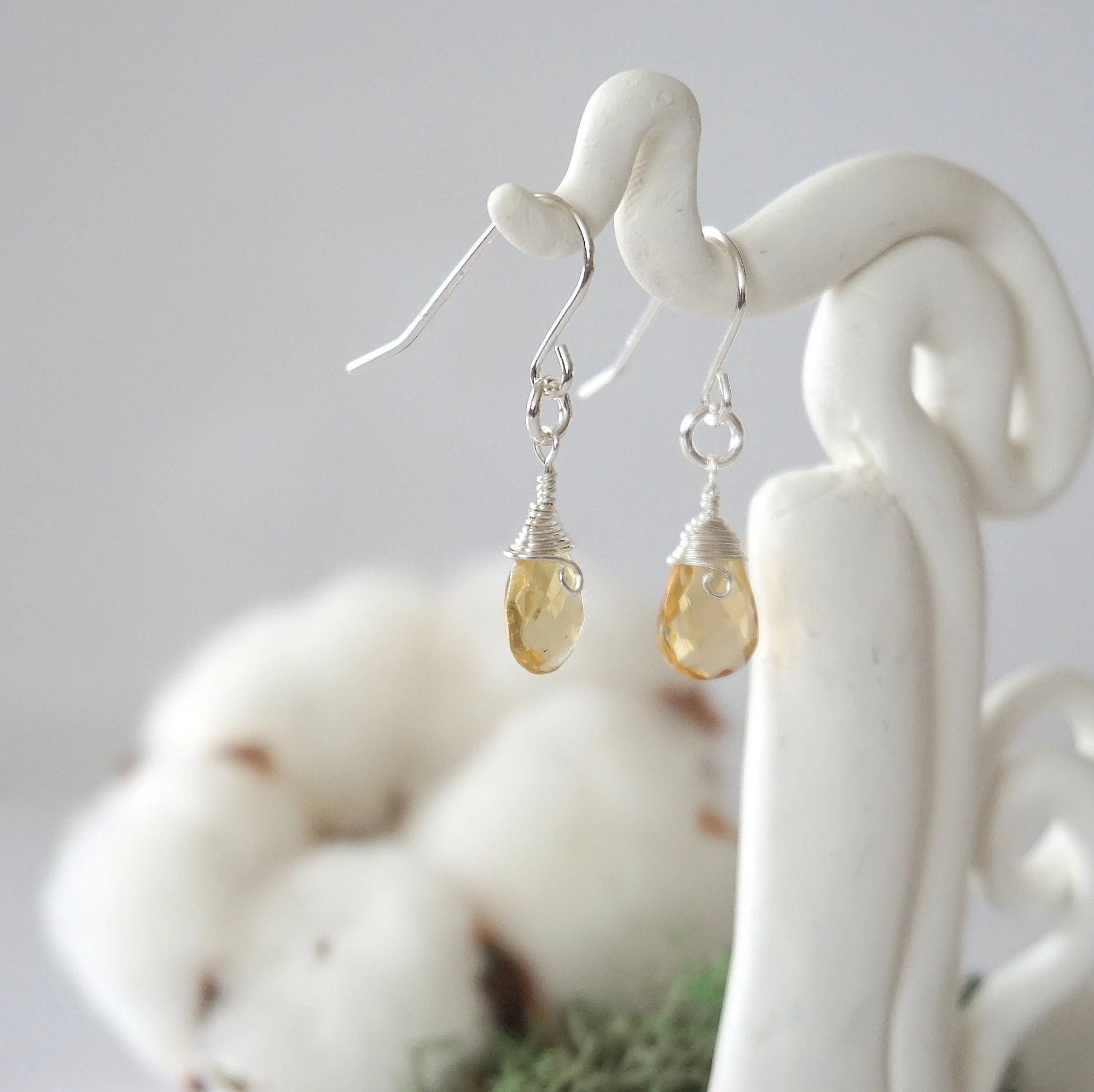 Side view of citrine sterling silver drop earrings showing wire wrapped natural faceted citrine, artisan craftsmanship, on a display – Designs by Nature Gems