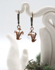 Close-up of handcrafted clear quartz drop earrings with antique bronze copper wire wrapping.