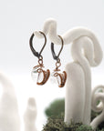 Side angle of clear quartz drop earrings on a display stand, highlighting antique bronze copper wire wrapping.