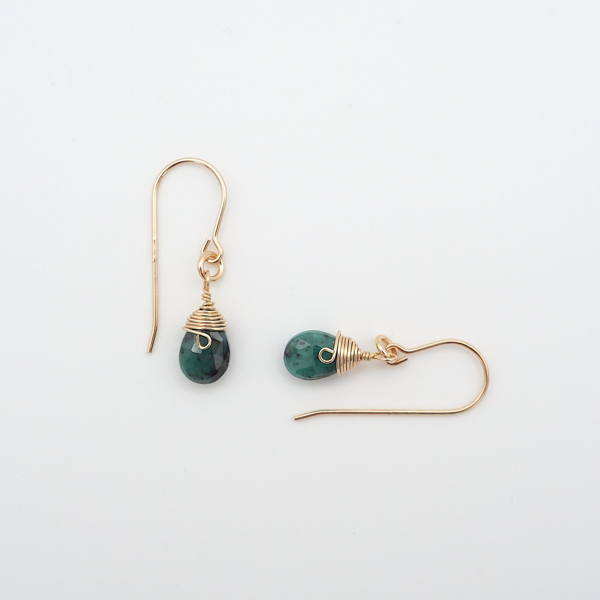 Closeup showing details of emerald drop earrings, faceted emerald stone, 14k gold filled setting
