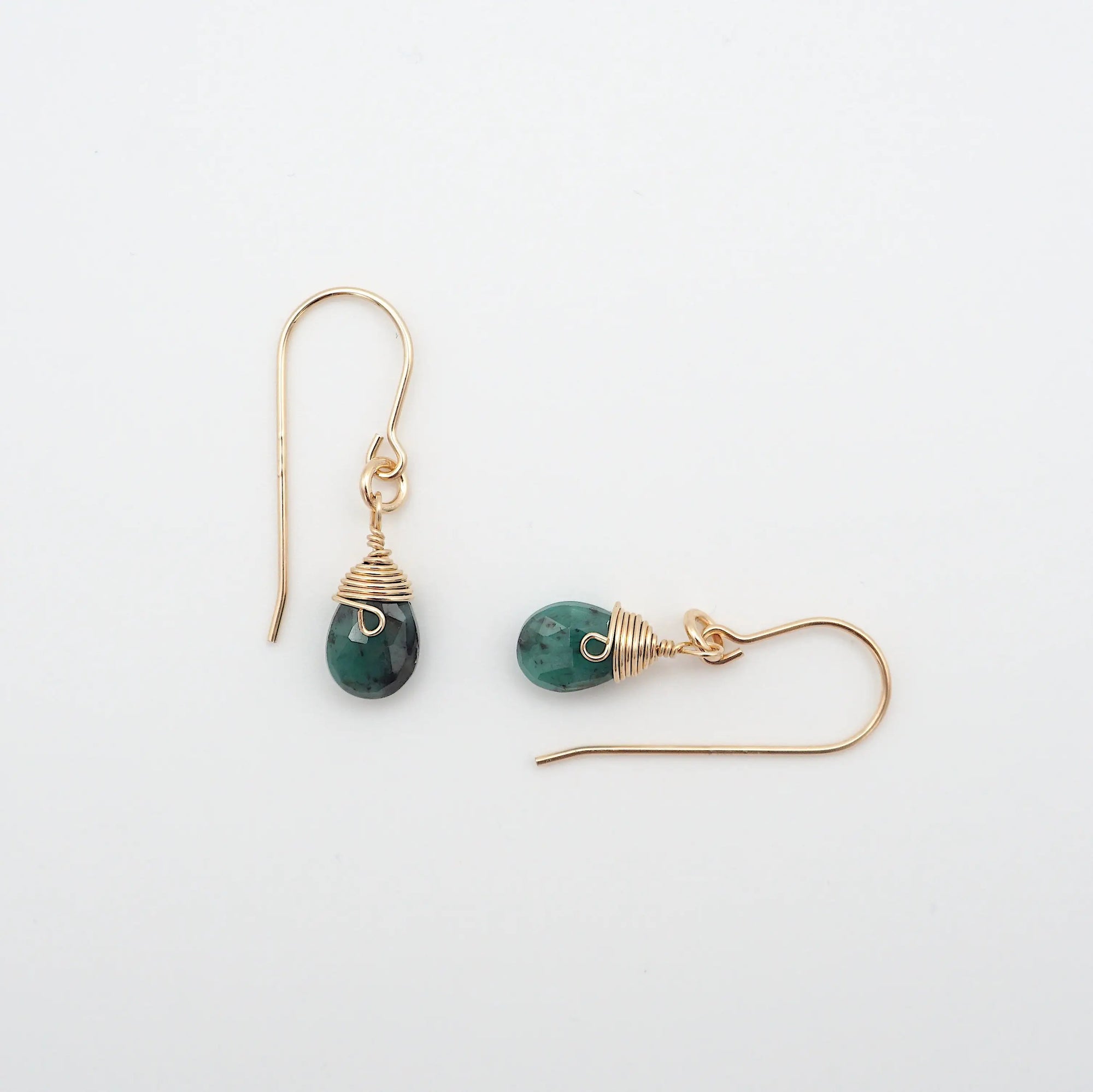 Closeup showing details of emerald drop earrings, faceted emerald stone, 14k gold filled setting
