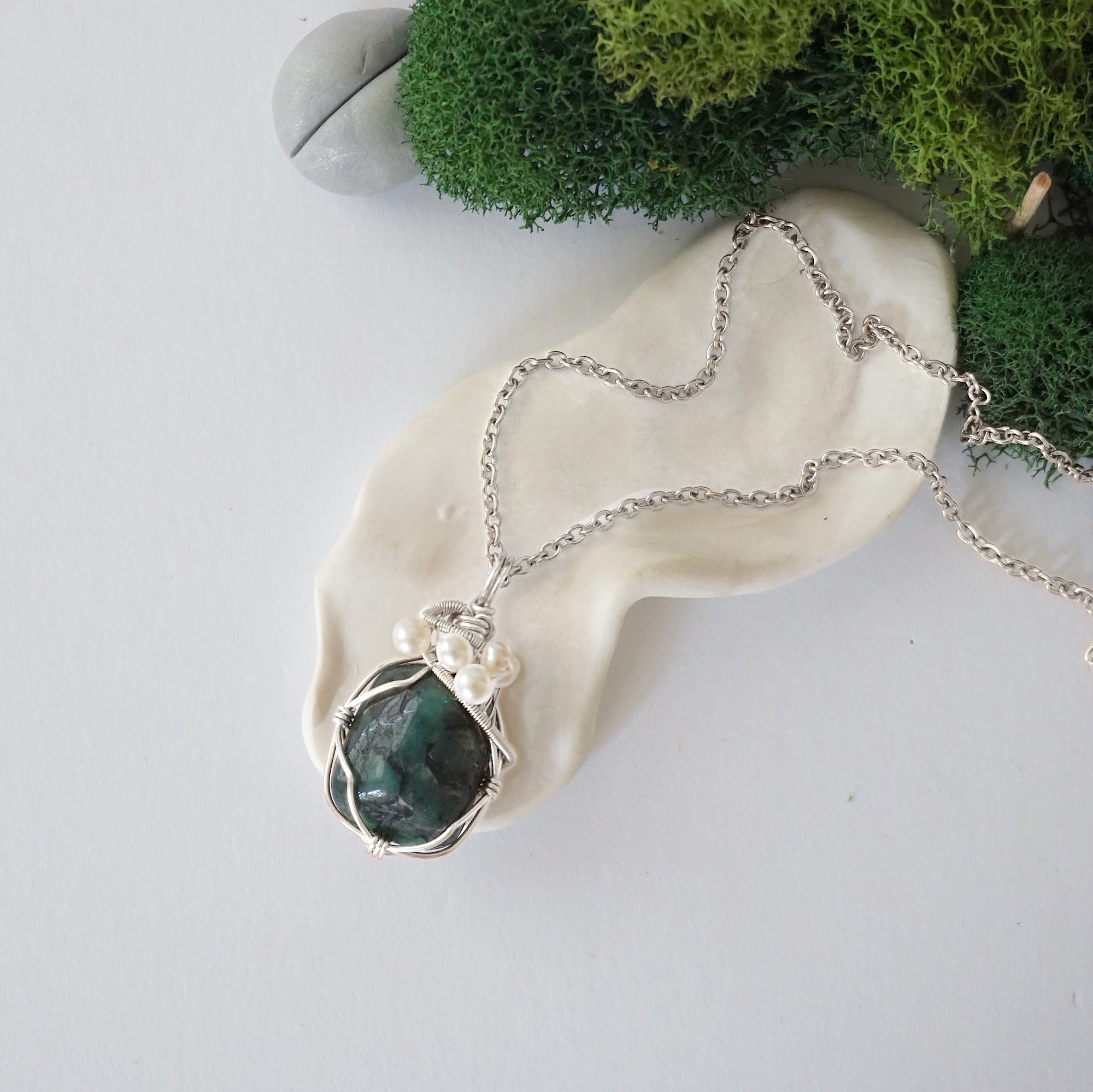 Handmade silver wire wrapped emerald and freshwater pearl necklace laying flat on a silver plated chain, artisan jewelry for women