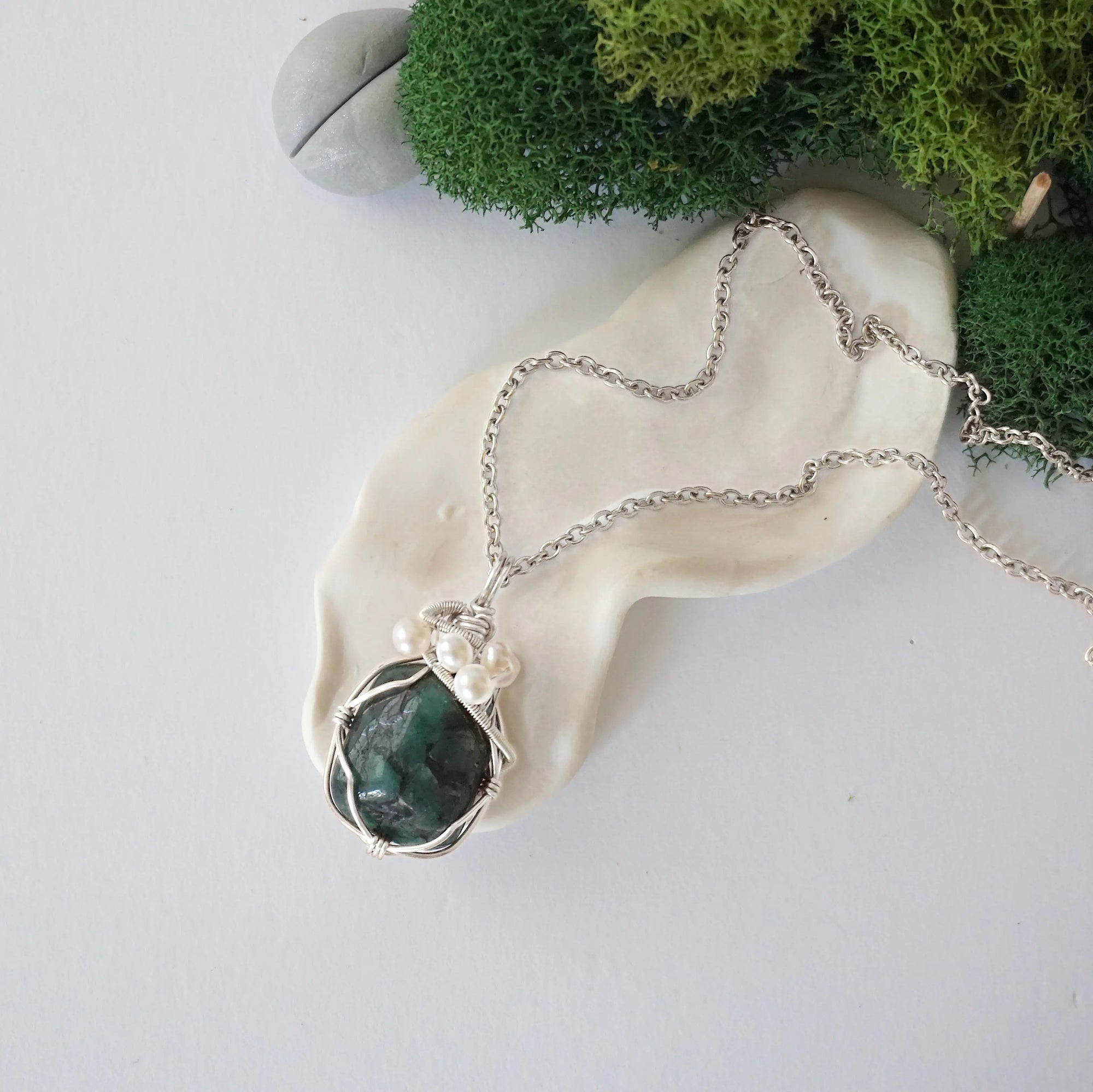 Handmade silver wire wrapped emerald and freshwater pearl necklace laying flat on a silver plated chain, artisan jewelry for women
