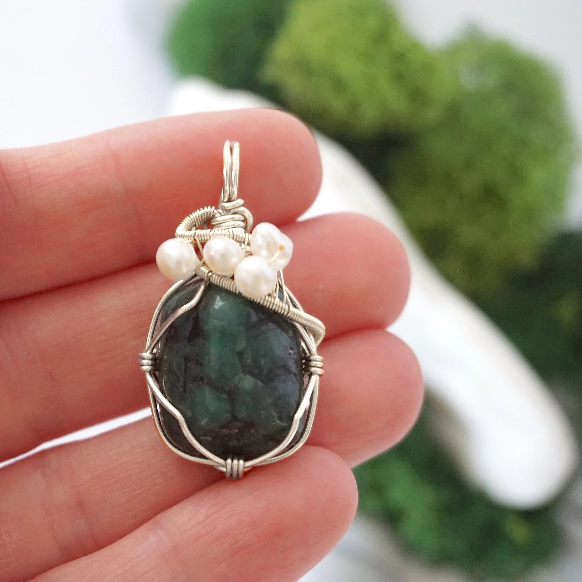 Emerald and freshwater pearl pendant necklace in hand for size reference, silver wire wrapped, handcrafted gemstone jewelry