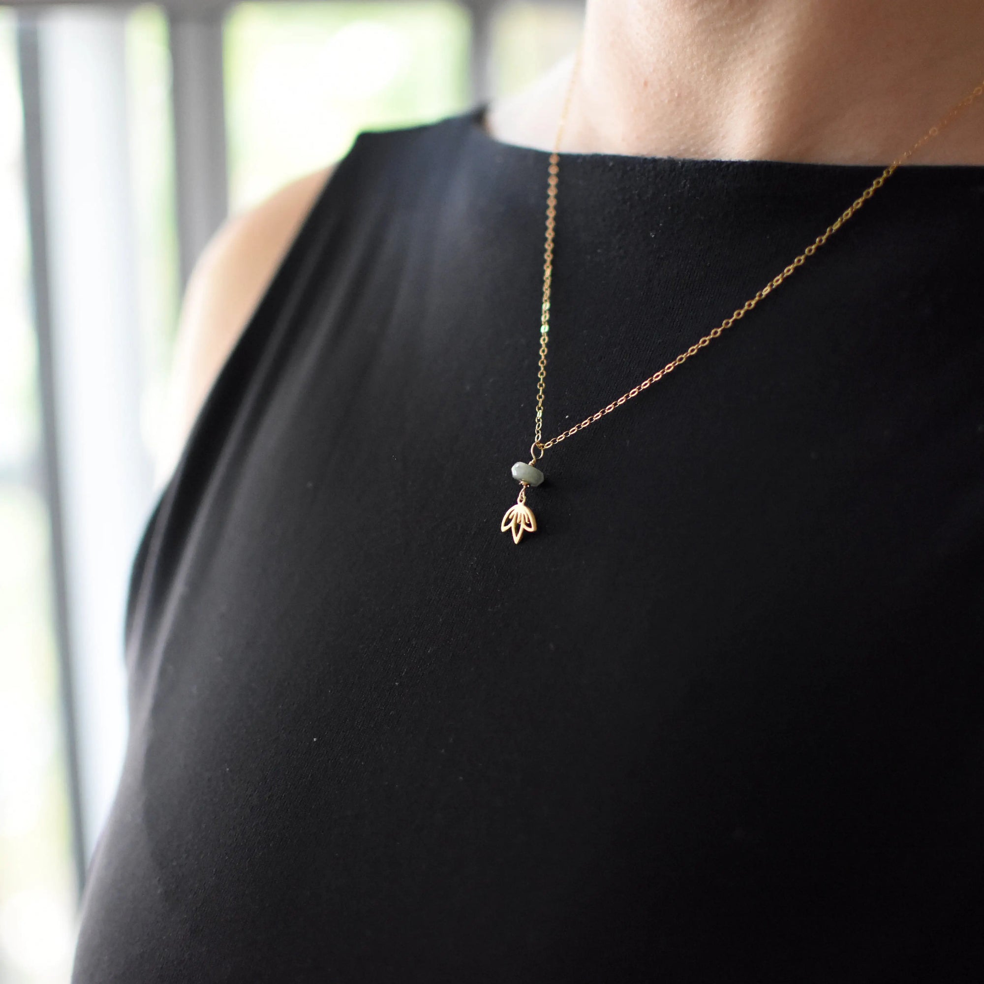 Emerald and lotus necklace for women worn on female model with natural emerald bead and gold vermeil lotus pendant