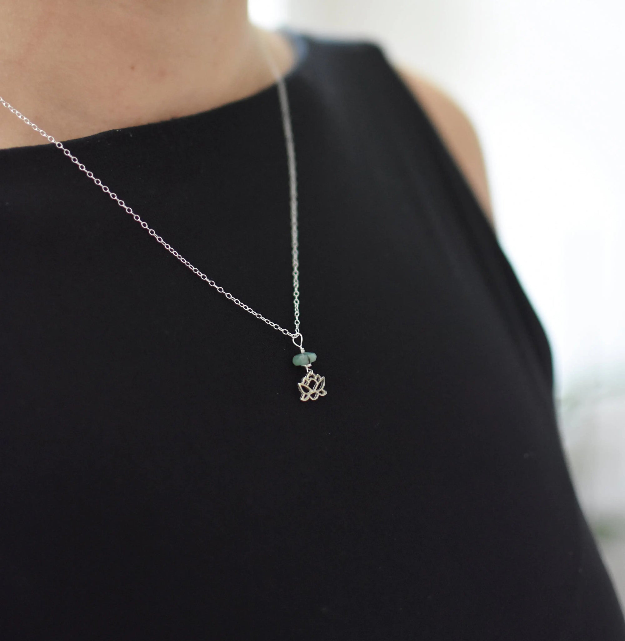 Emerald and lotus necklace for women worn on female model with natural emerald bead and sterling silver lotus pendant