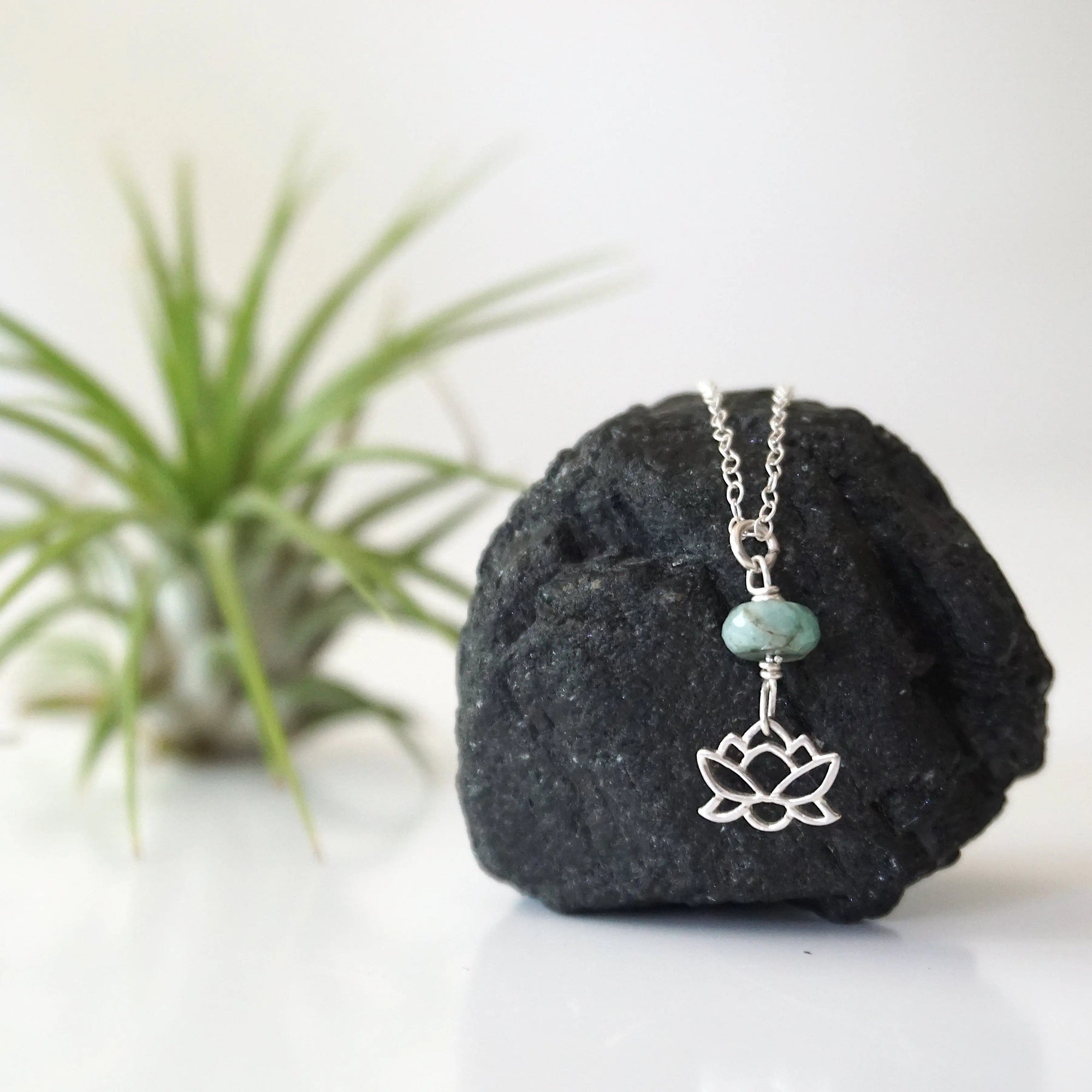 Zoomed out view of emerald and lotus necklace for women with sterling silver lotus charm on fine chain
