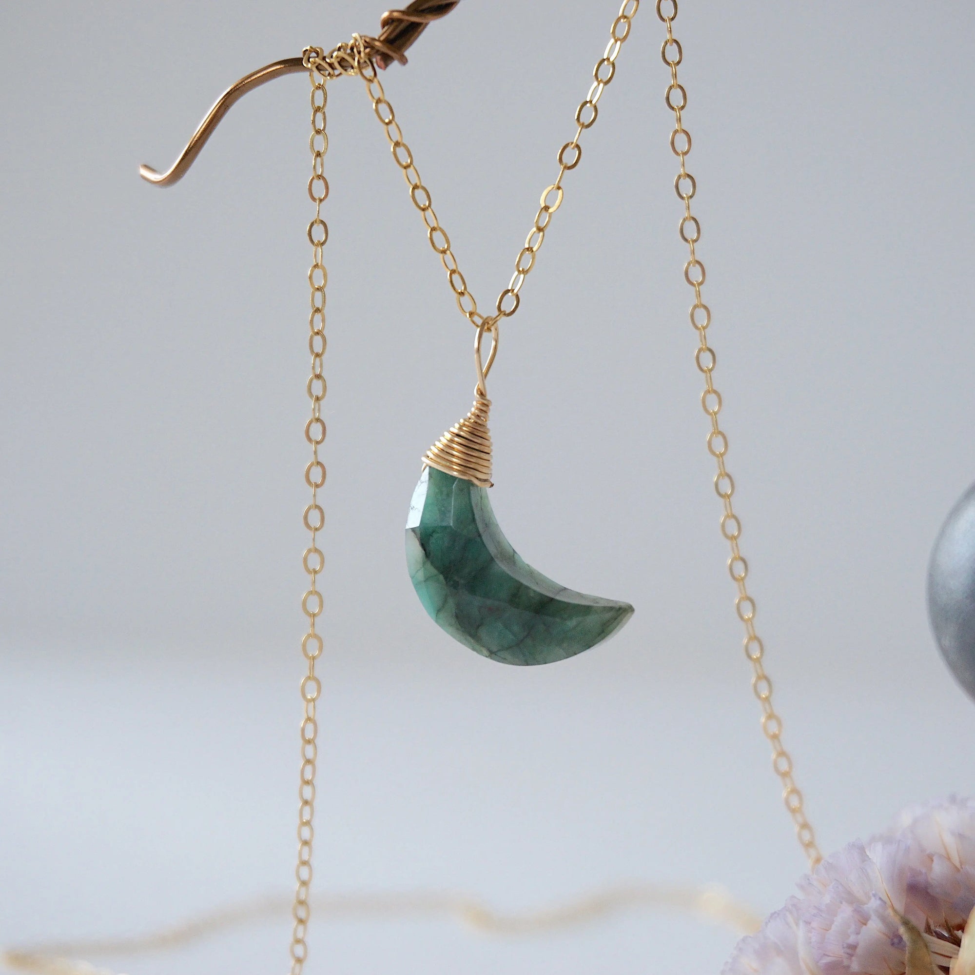 Left angle detail of faceted emerald moon necklace for women with classic artisan 14k gold filled wrapping