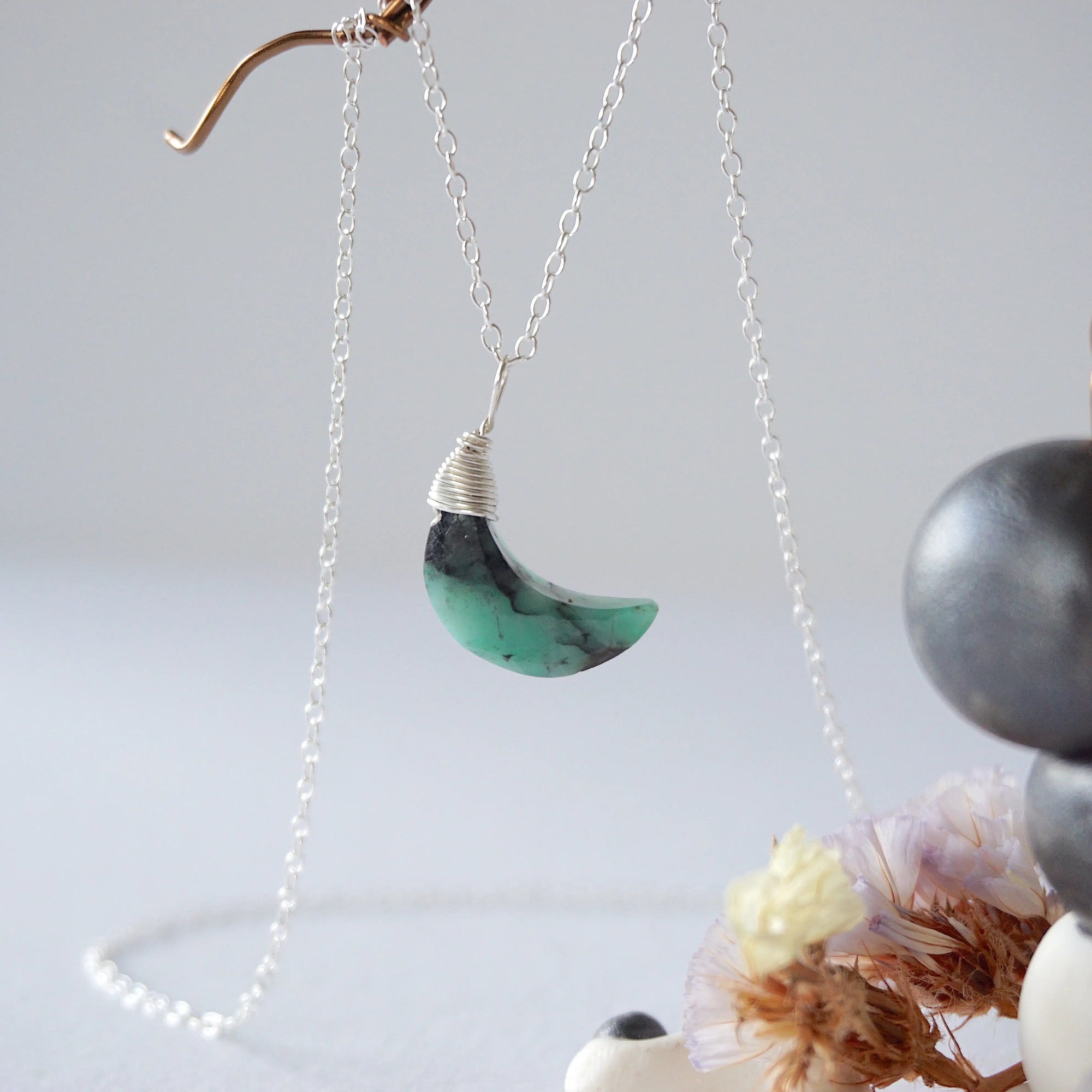 Left angle detail of faceted emerald moon necklace for women with classic artisan 925 sterling silver wrapping