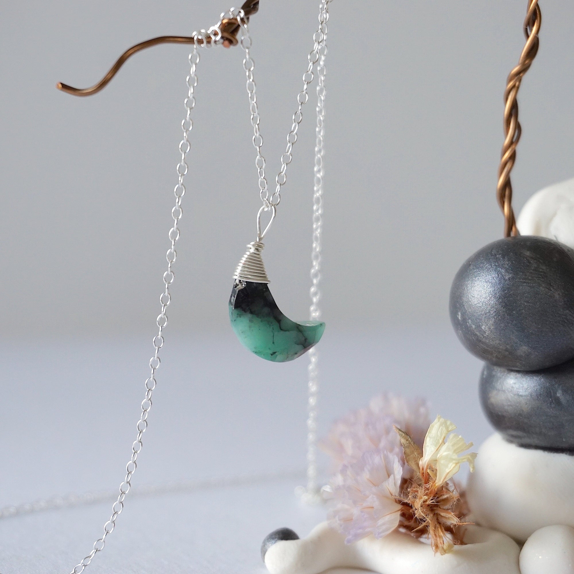 Right angle detail of emerald moon necklace for women with natural faceted emerald and handcrafted sterling silver wire wrapping