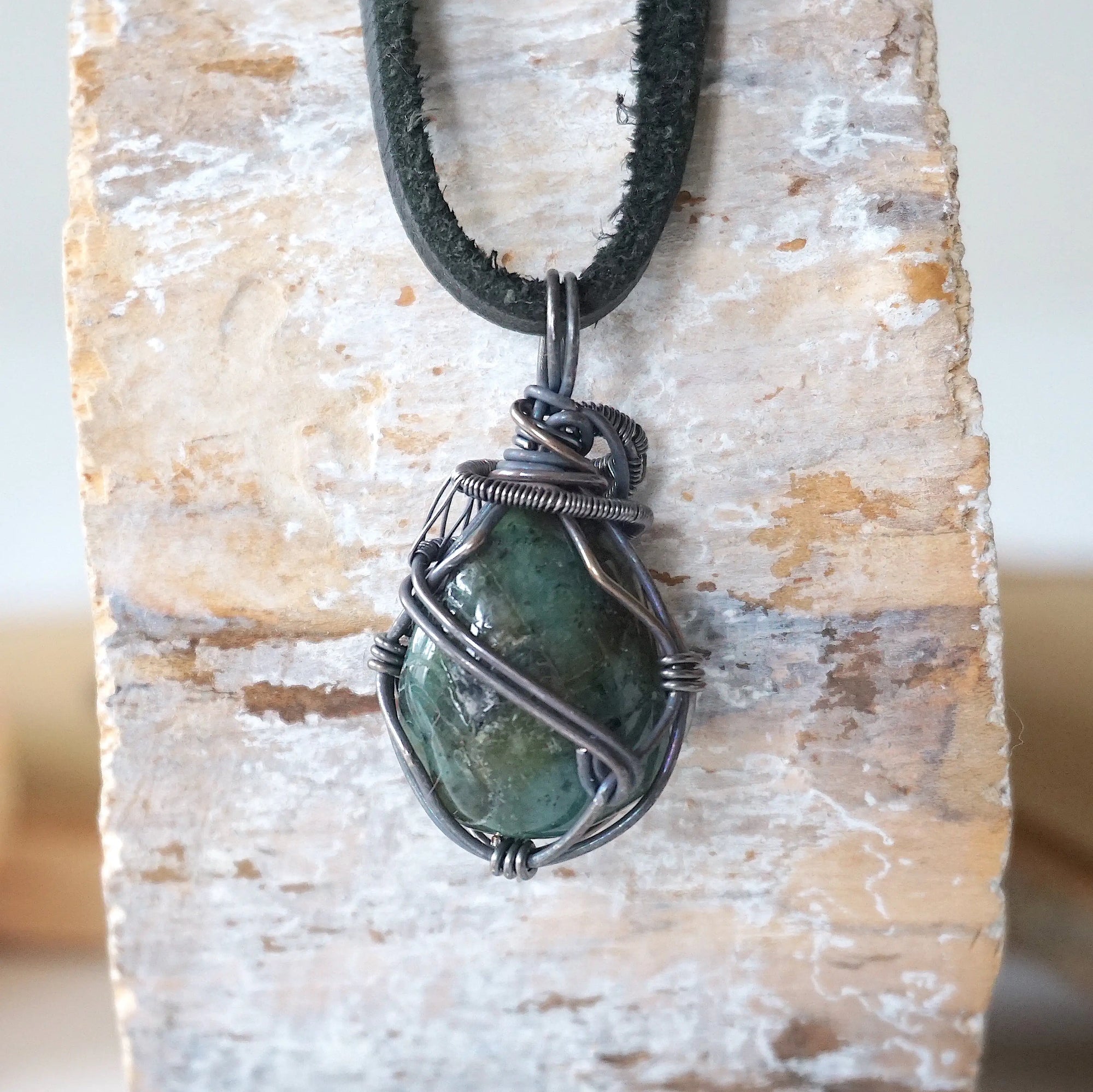 Back angle view of emerald necklace for men with natural polished-raw emerald and detailed antiqued sterling silver craftsmanship