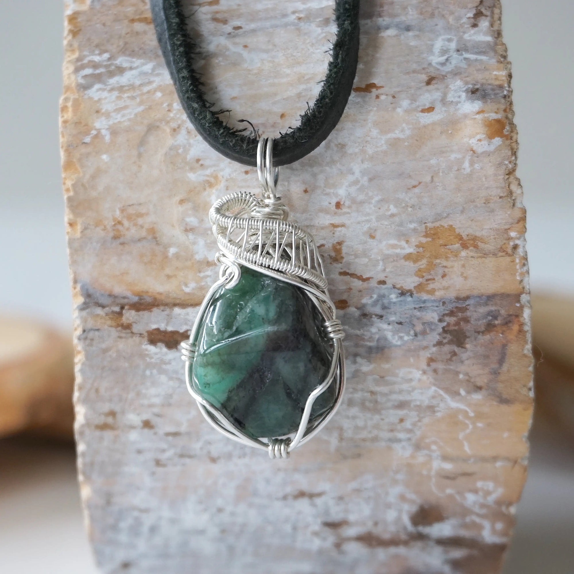 Detailed view of emerald necklace for men with natural polished-raw emerald and 925 sterling silver wire wrapping.