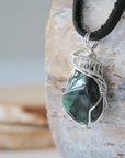 Left angle view of emerald pendant for men highlighting polished-raw emerald and artisan sterling silver wrapping.