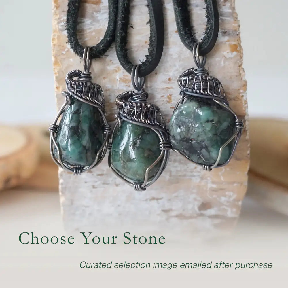 Three emerald pendants for men showing natural variation in emerald size, shape, and green colour in antiqued sterling silver wrapping