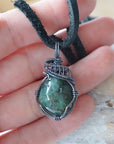 Emerald pendant necklace for men shown in hand for size reference with natural polished-raw emerald and antiqued sterling silver