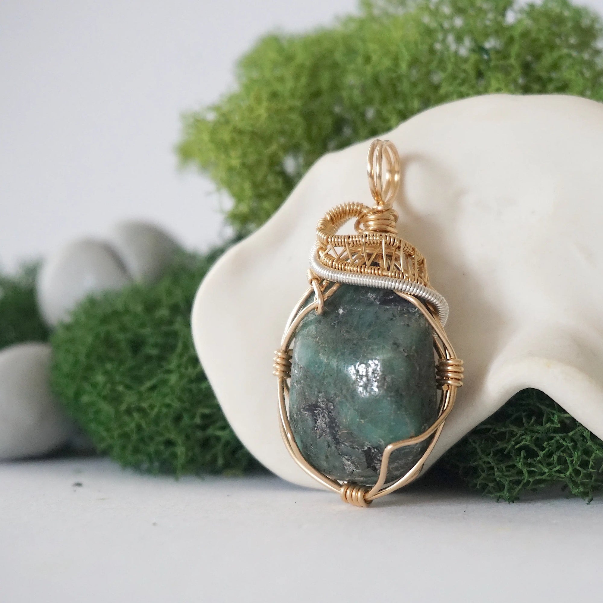 Left angle view of emerald necklace for women with natural polished-raw emerald and detailed mixed metal wire wrapping in gold filled and sterling silver
