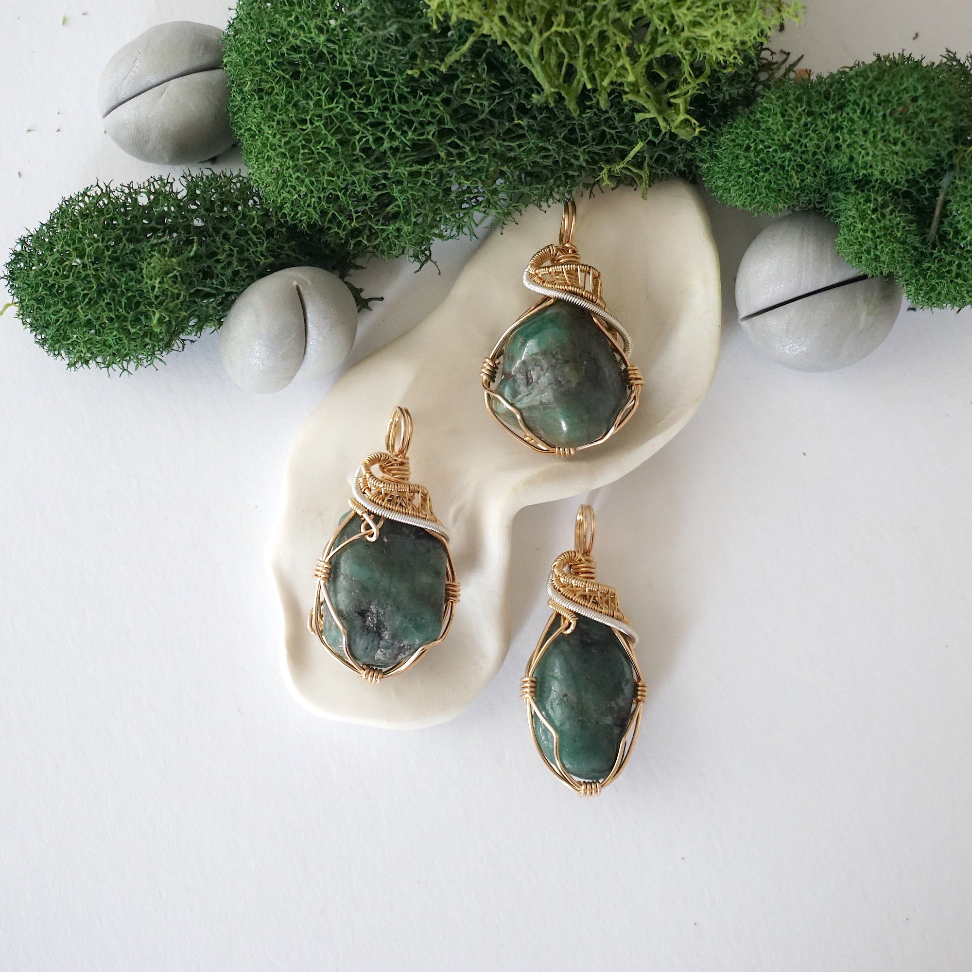 Three emerald pendants for women showing natural variation in emerald size, shape, and green colour with 14k gold filled and sterling silver wire wrapping