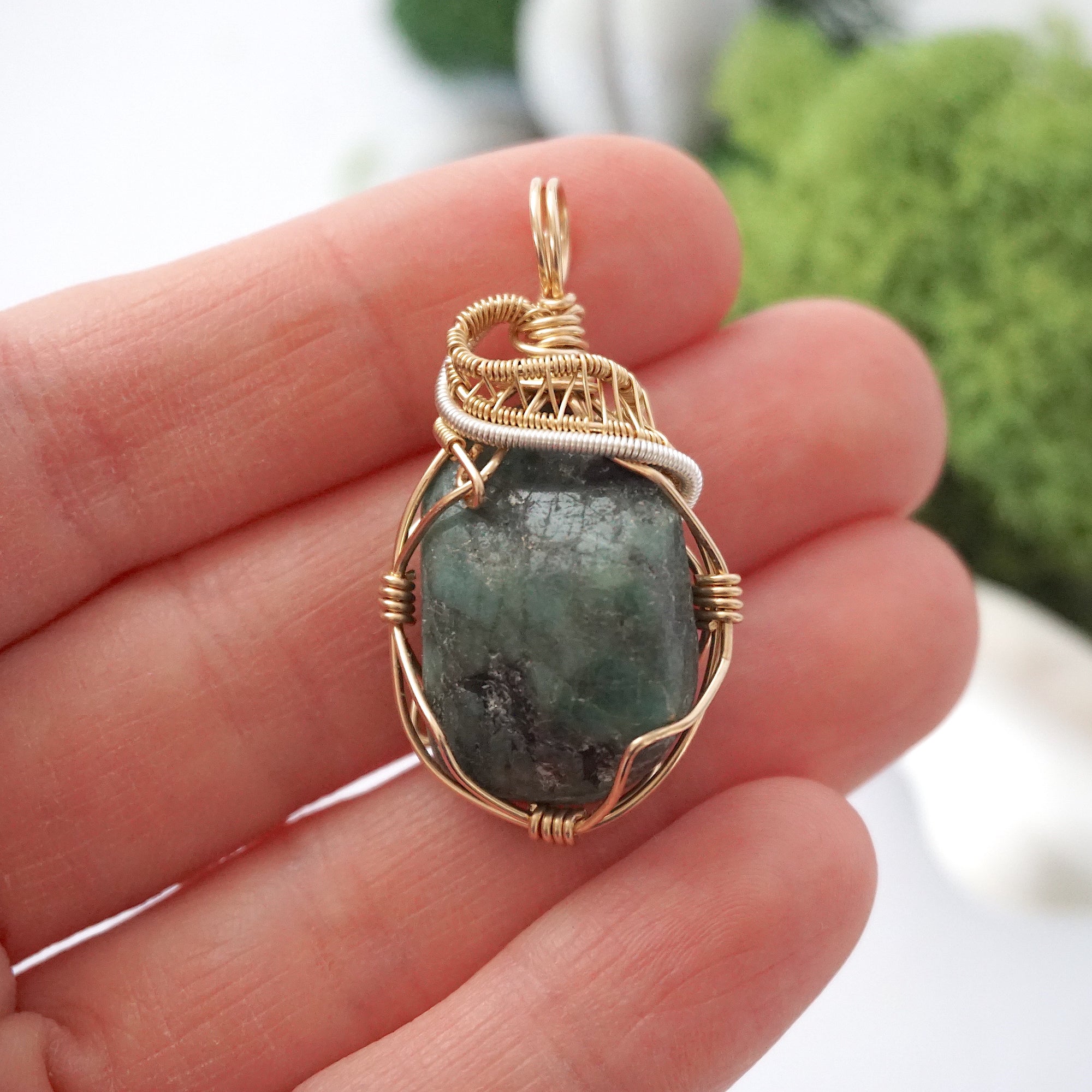 Emerald pendant necklace for women shown in hand for size reference with natural polished-raw emerald in 14k gold filled and sterling silver wire wrapping