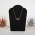 Emerald and freshwater pearl bar necklace in 925 sterling silver on jewelry display, front view