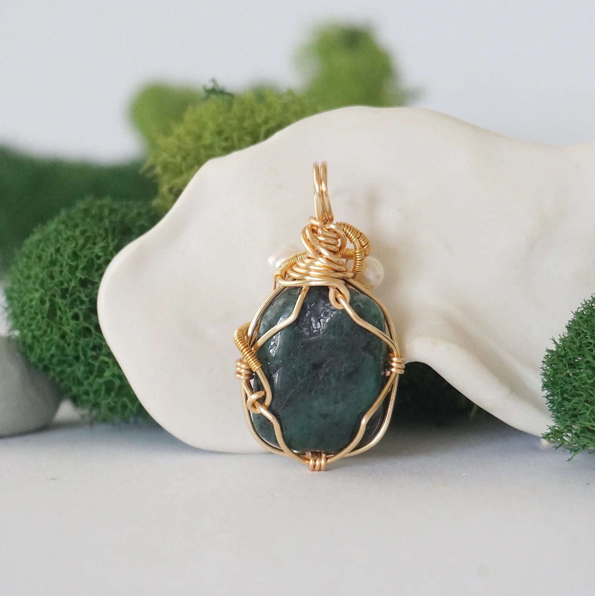 Back angle detail of emerald and freshwater pearl pendant, showing wire wrapping and natural stone