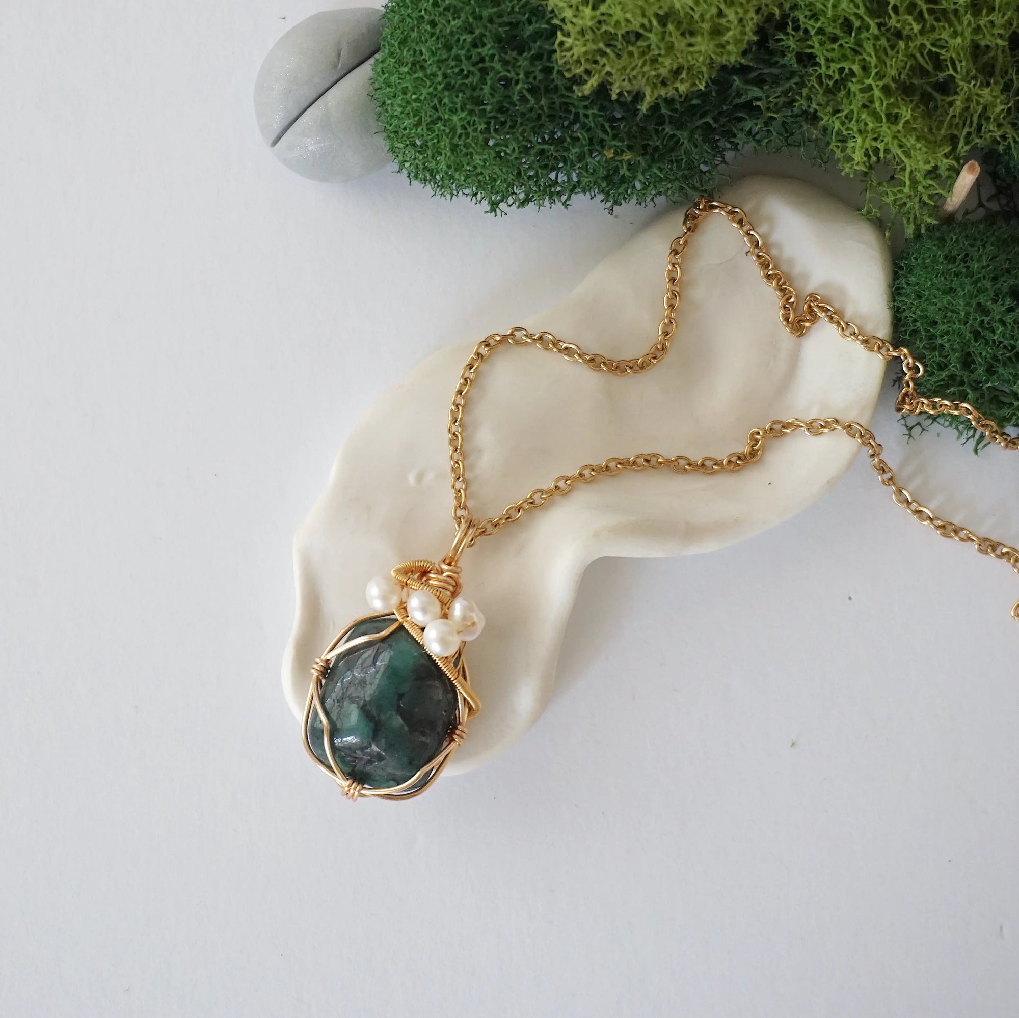 Emerald and freshwater pearl pendant on gold plated brass chain laying flat, handmade wire wrapped jewelry for women