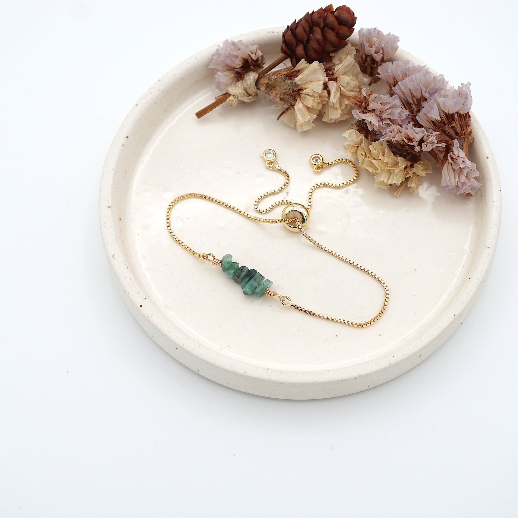 Handmade emerald bracelet displayed on ceramic tray showing natural green crystals and gold chain - May birthstone gift for her