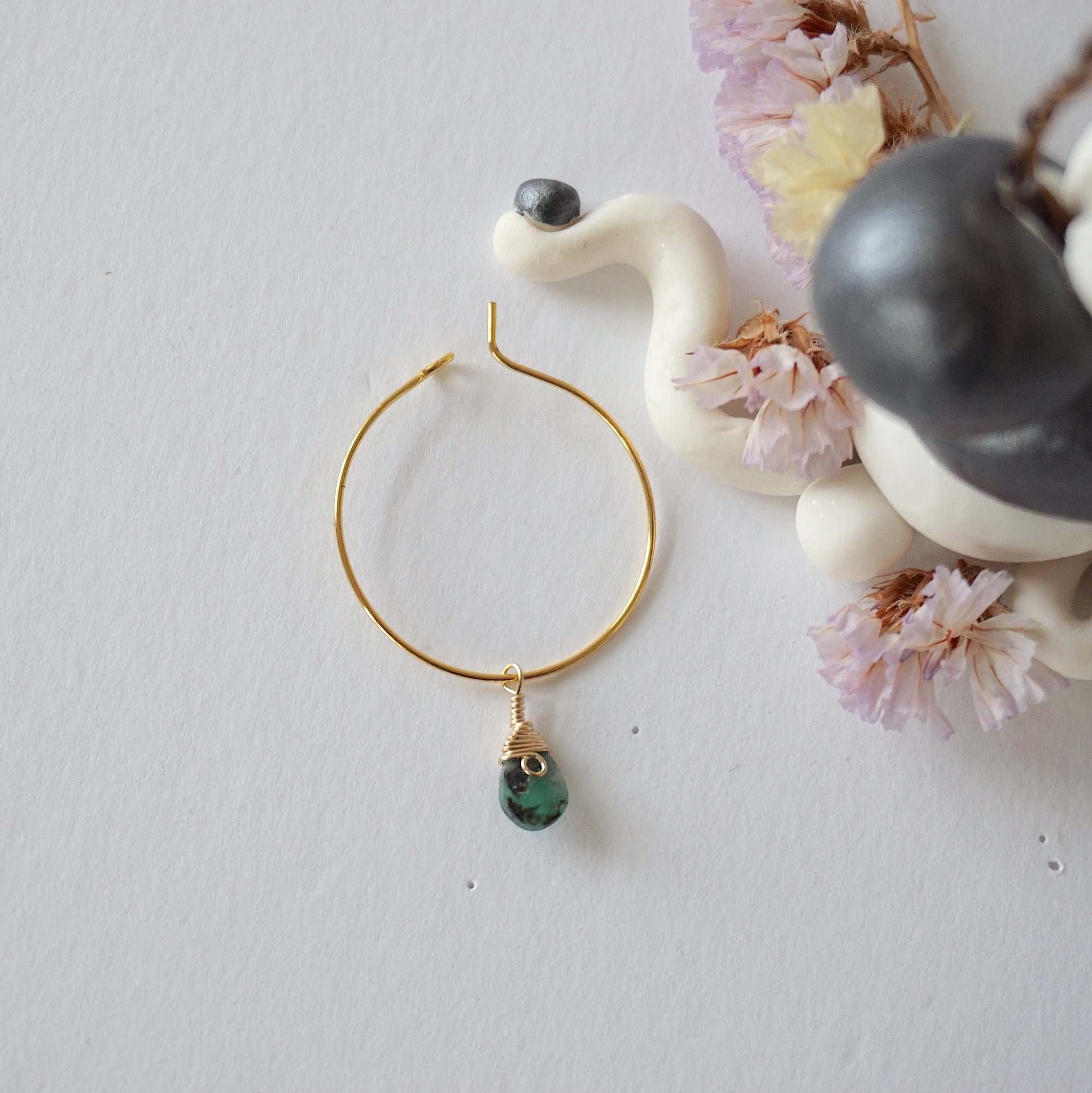 Emerald hoop drop earrings on flat surface showing faceted emerald drop and classic warm gold hoop design