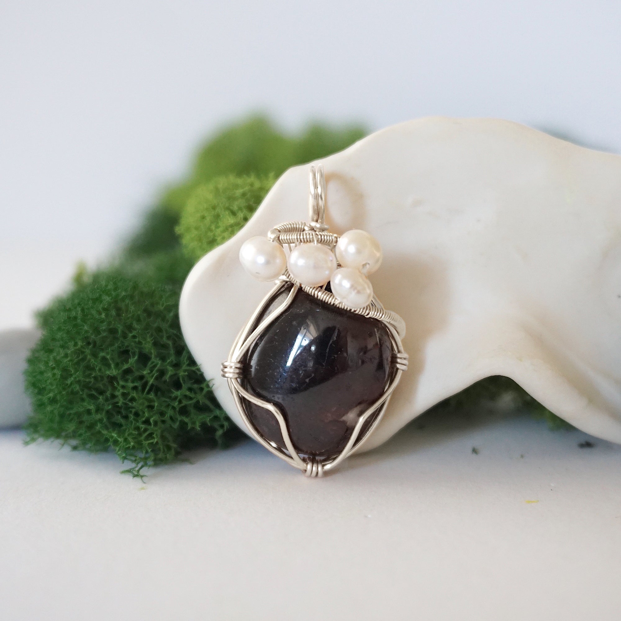 Detailed front view of silver wire wrapped garnet and freshwater pearl pendant, unique artisan necklace