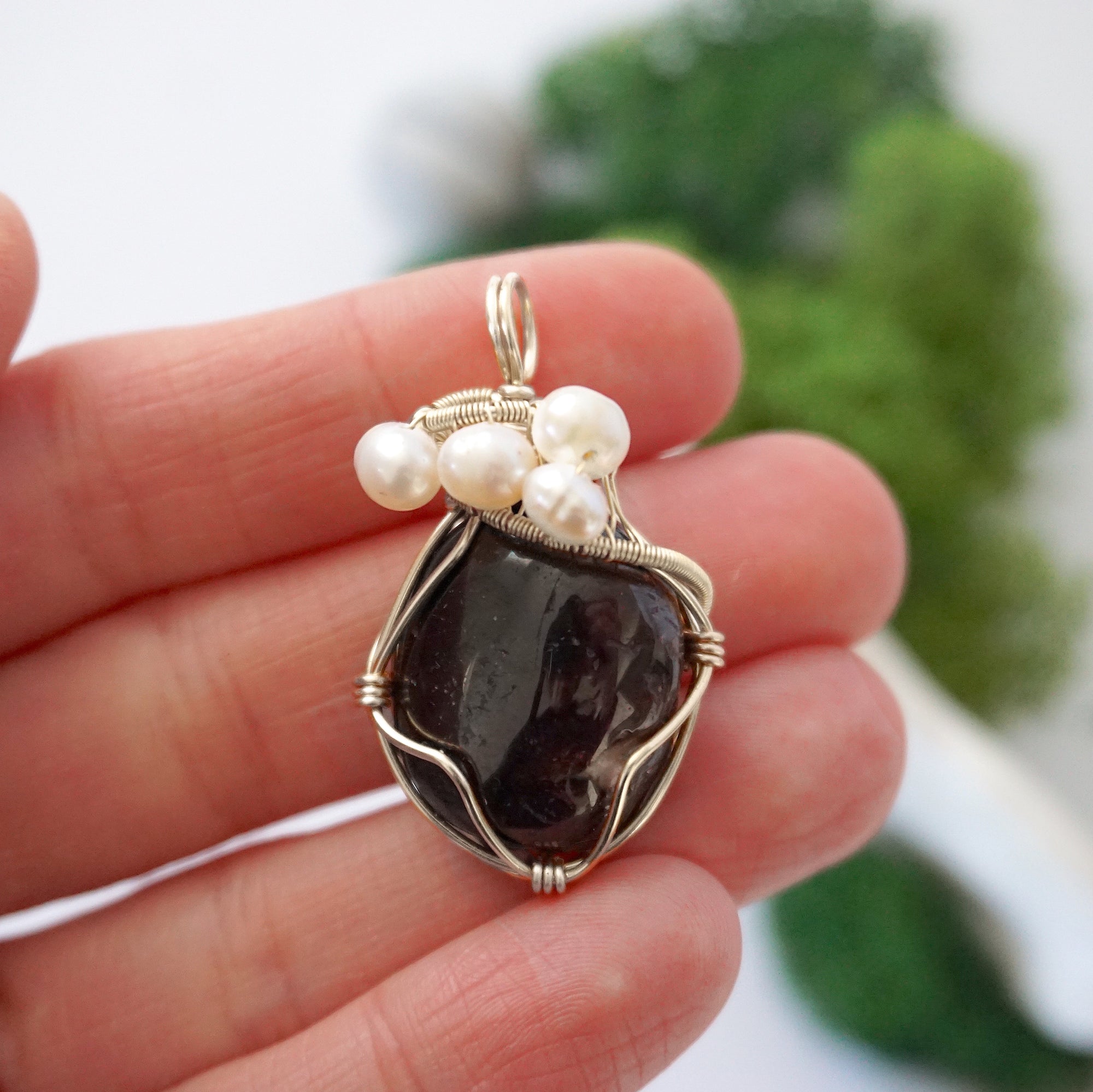 Garnet and freshwater pearl pendant necklace in hand for size reference, silver wire wrapped, handcrafted gemstone jewelry