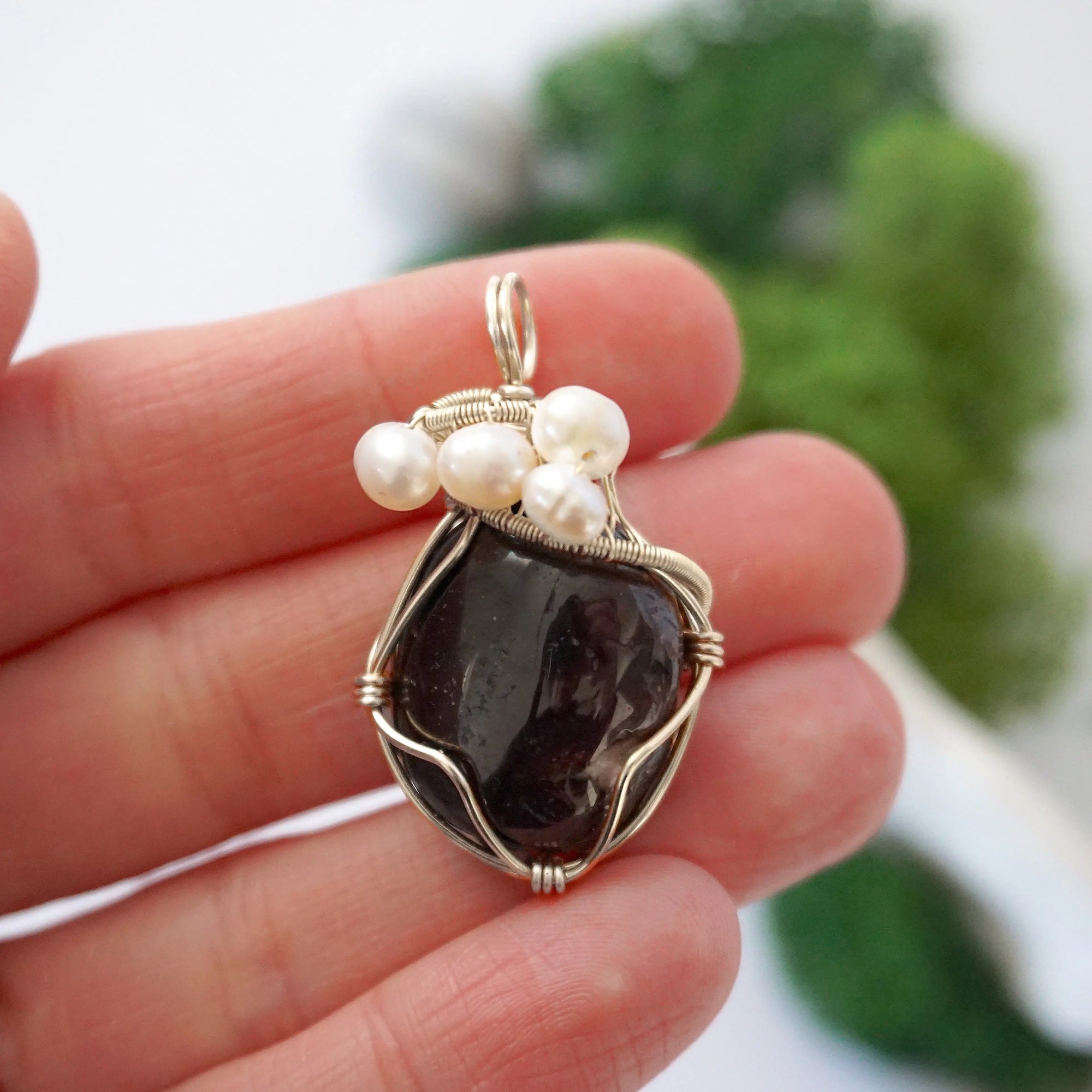 Garnet and freshwater pearl pendant necklace in hand for size reference, silver wire wrapped, handcrafted gemstone jewelry