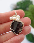 Garnet and freshwater pearl pendant necklace in hand for size reference, silver wire wrapped, handcrafted gemstone jewelry
