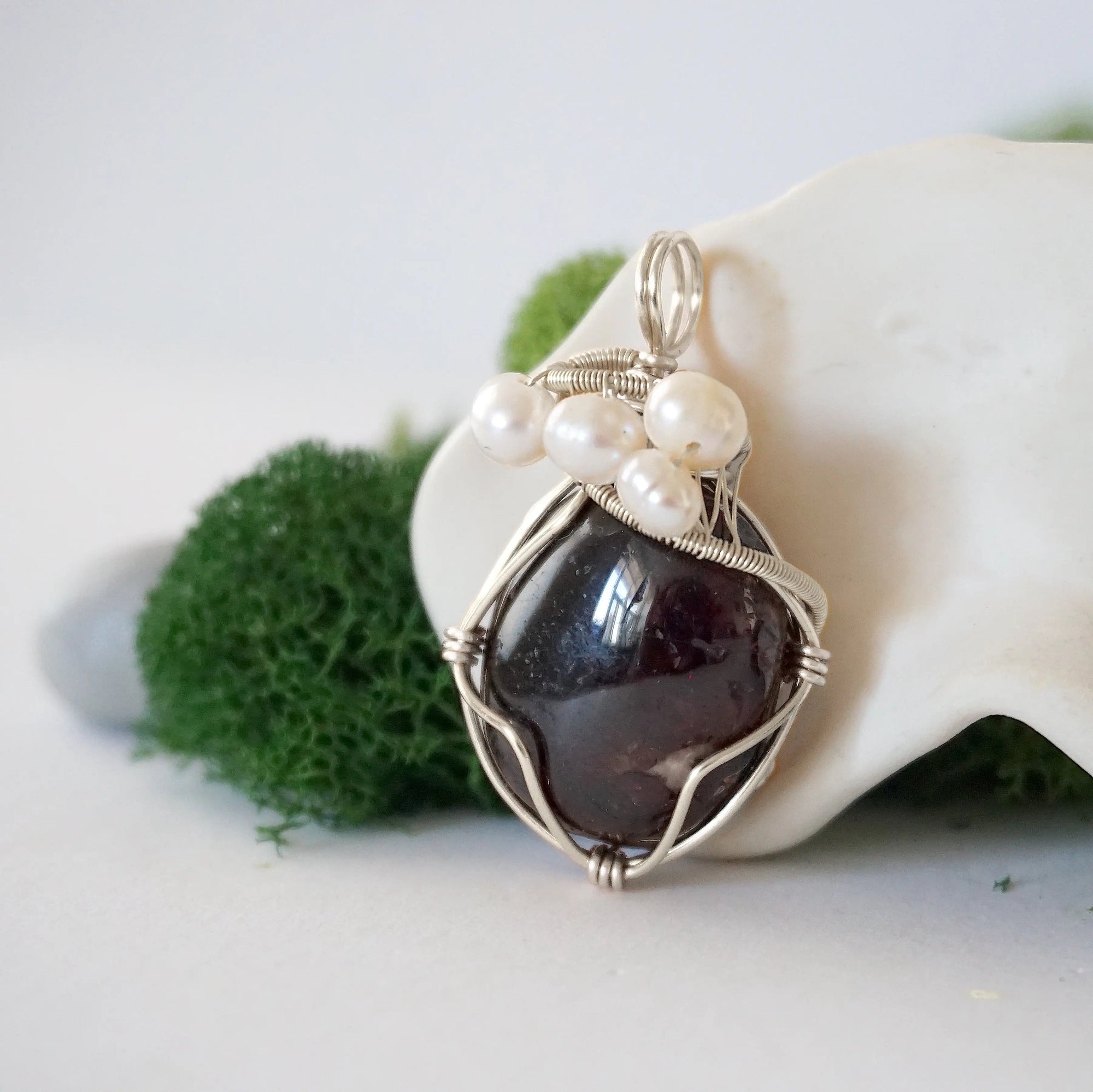 Side angle of handmade garnet and freshwater pearl pendant necklace, silver wire wrapped jewelry